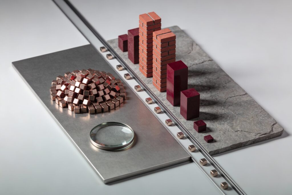 Maquette physique montrant une plaque métallique divisée entre un bloc compact de cubes représentant un ETF actions cap-pondéré et plusieurs colonnes de blocs smart beta, avec des jetons rouges de flux qui s’accumulent dans une seule zone, symbolisant le risque de concentration caché lorsque les ETF smart beta attirent des flux massifs en 2025